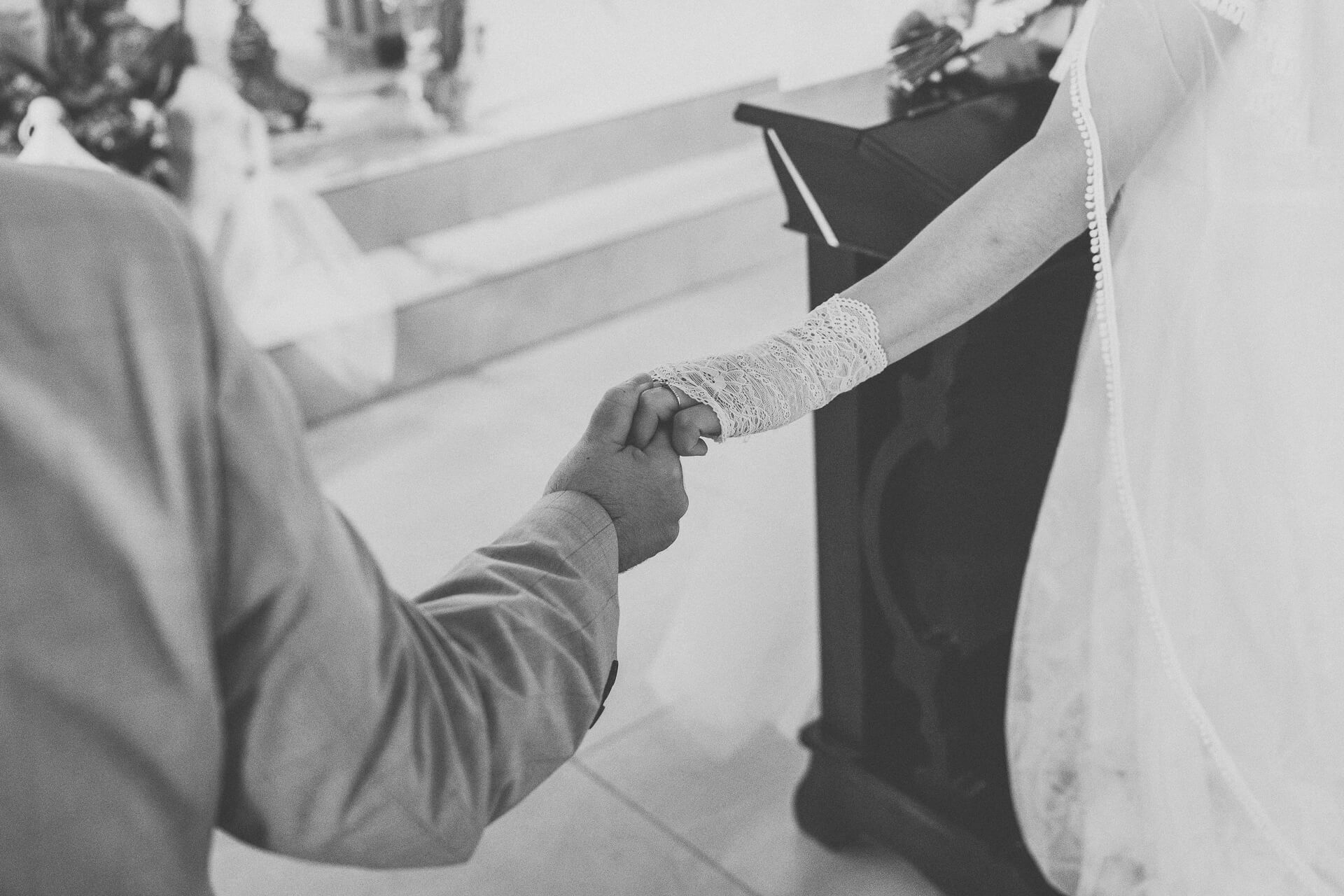 Para młoda trzymająca się za ręce podczas ceremonii ślubnej